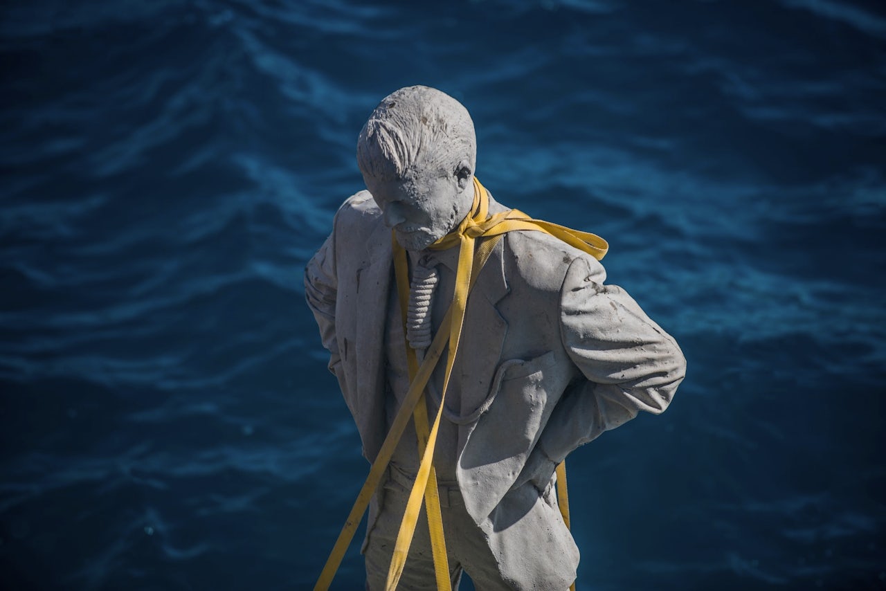 A statue is prepared to be lowered to the ocean floor.