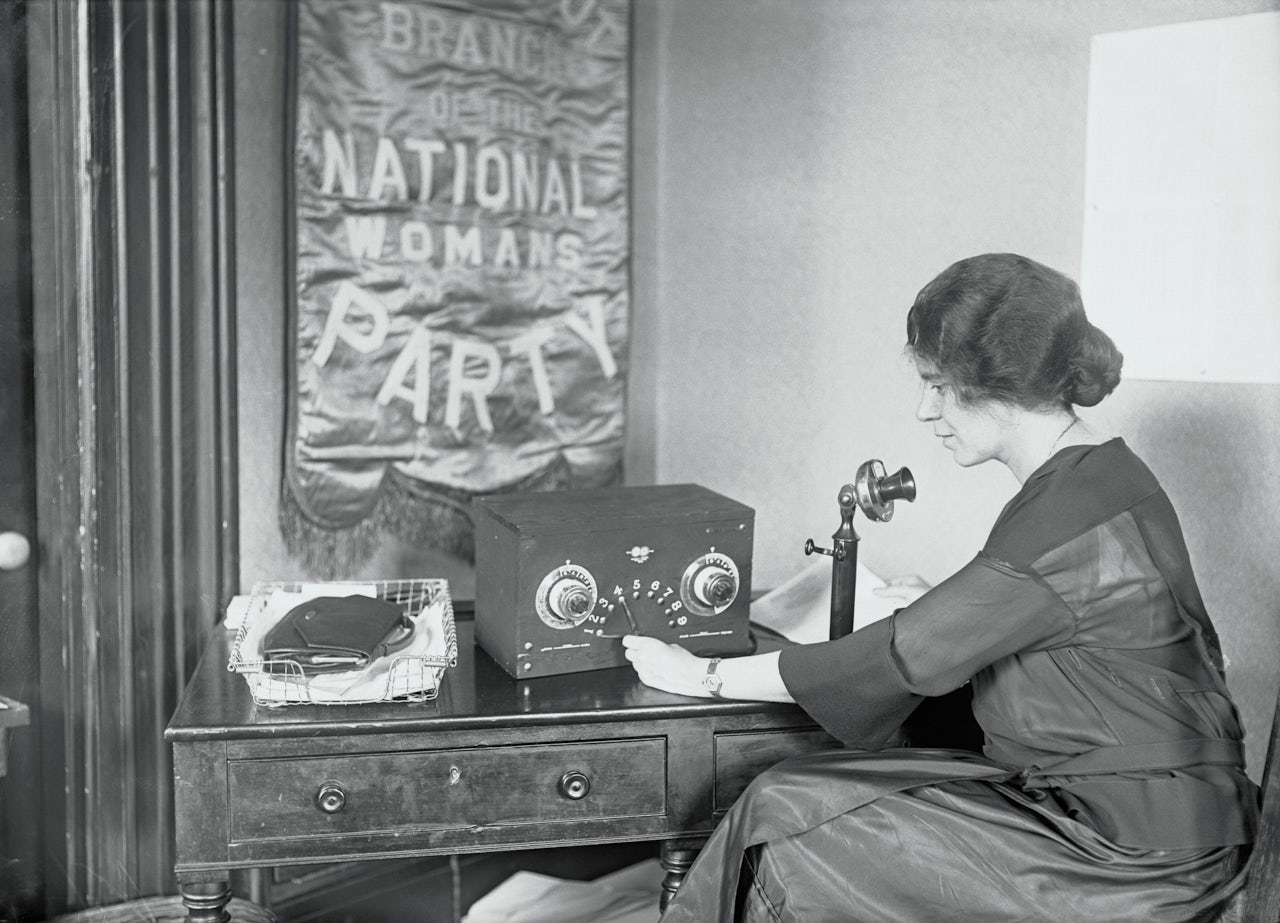 Alice Paul, vice president of the National Woman's Party, broadcasts plans for the dedication of the New National Headquarters at Washington from her desk at the Capitol.