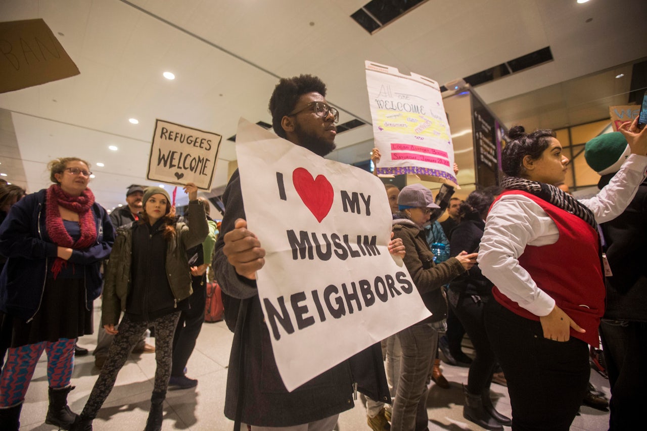 A protester holds up a sign that reads 'I Love My Muslim Neighbors' during a demonstration against the new ban on immigration issued by President Donald Trump at Logan International Airport.