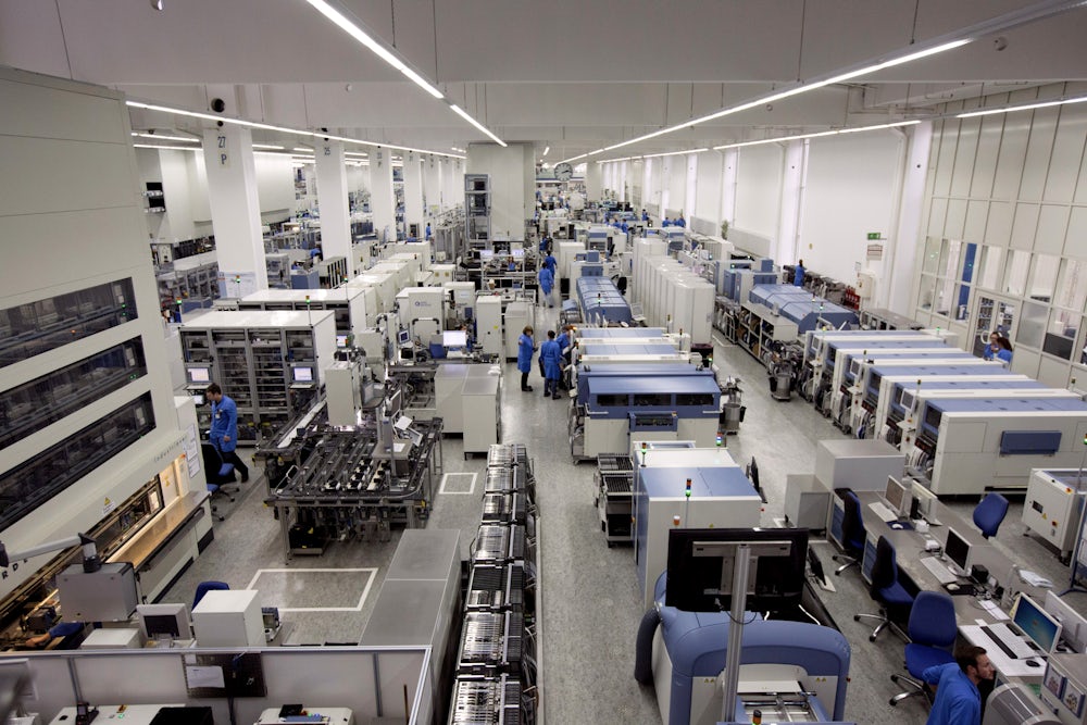 Employees work on the automated assembly line at the Siemens AG electronics factory in Amberg, Germany.