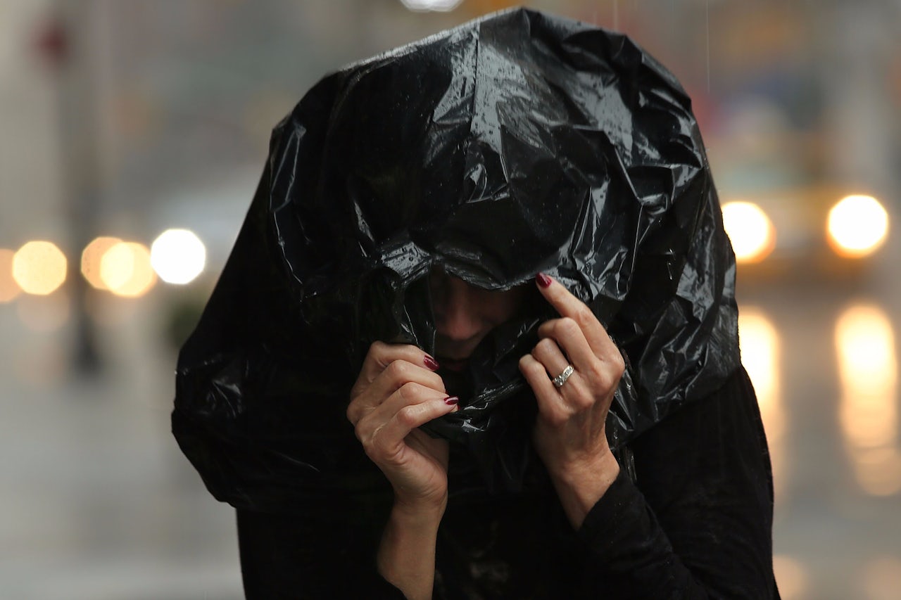 A woman shields herself from rain in New York City.