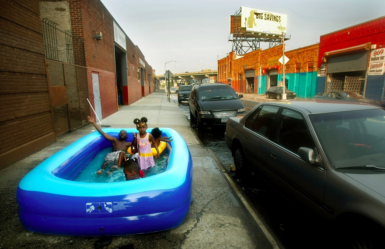 New Yorkers enjoy an inflatable pool on a sidewalk in the Bronx.