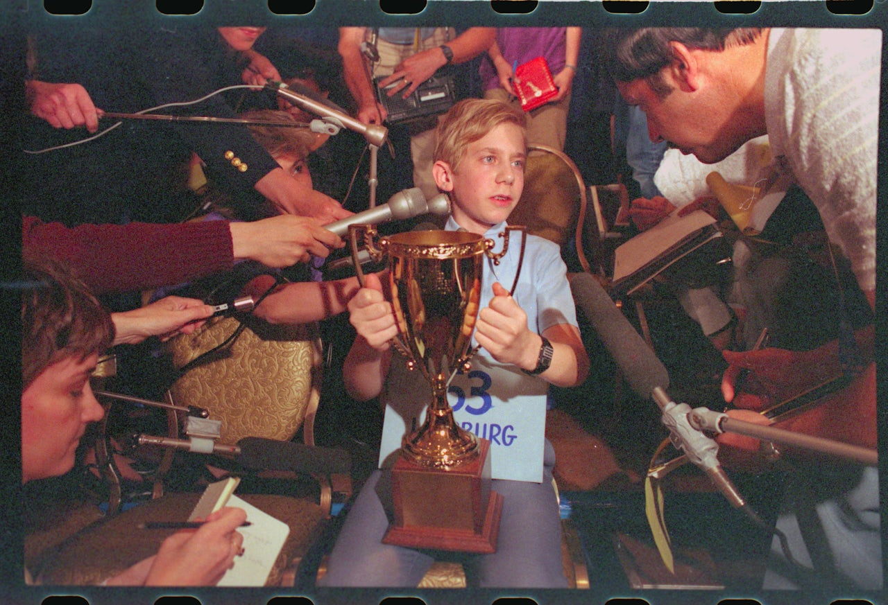 The 1984 Scripps National Spelling Bee winner, 13-year-old Daniel Greenblatt, shows off his trophy to gathered reporters.