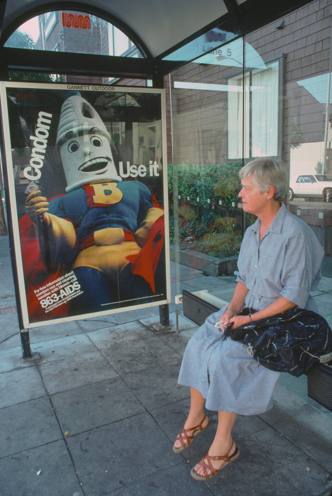 A commuter sits next to a PSA at a bus stop in San Francisco in 1989.