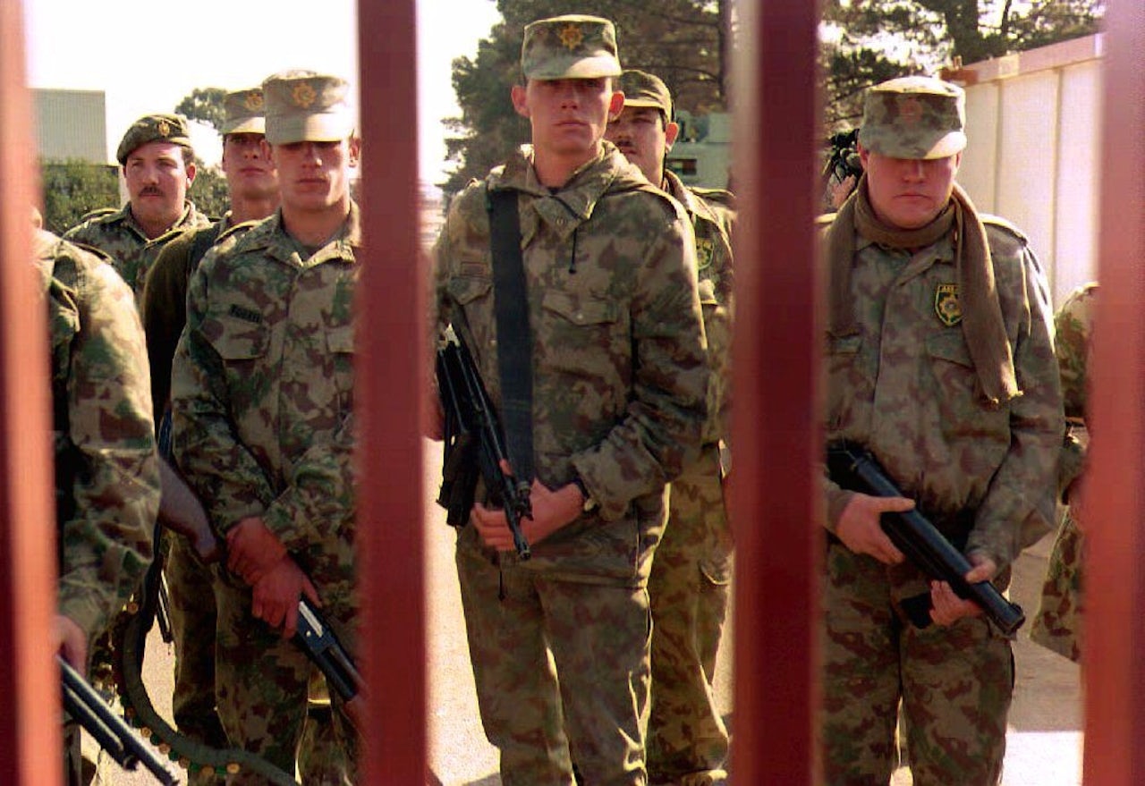 South African police take up positions behind a steel gate at the World Trade Center in Kempton Park after white racial militants stormed the compound.