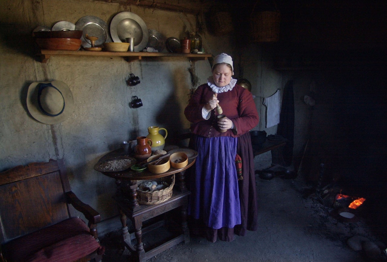 An interpreter prepares fritters in her one-room house at Plimoth Plantation in 2003.