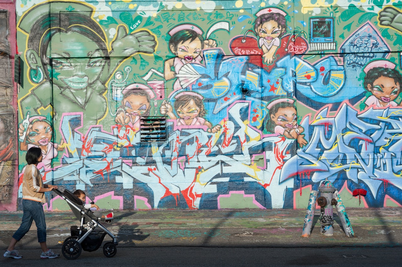 A woman walks past a mural by artists Shiro, Meres One, and Demer at 5Pointz in 2012.