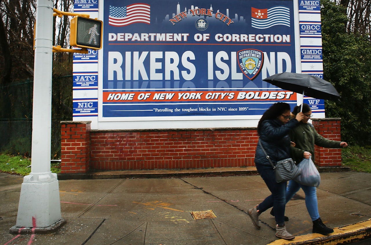 People walking by the entrance to Rikers Island, 2017.