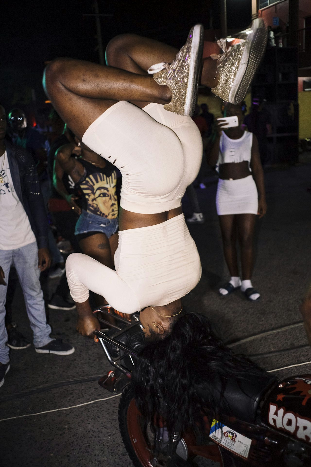A dancer goes “pon di head top” on the back of a motorcycle while DJ Ruxie and Jazzy T play the latest dancehall singles.