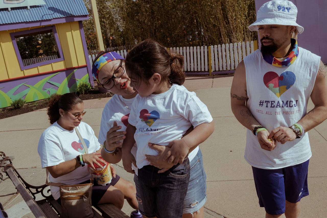 A family wearing matching #TeamCJ shirts share a moment on a park bench. Some families conduct fundraising for autism research and treatment, using team names dedicated to the name of a loved one who has autism.