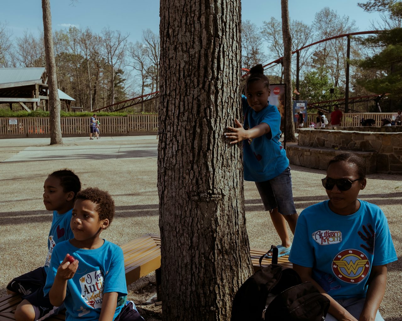 A mother and group of children relax in the shade of a tree and have a snack in one of the less crowded areas of the park.