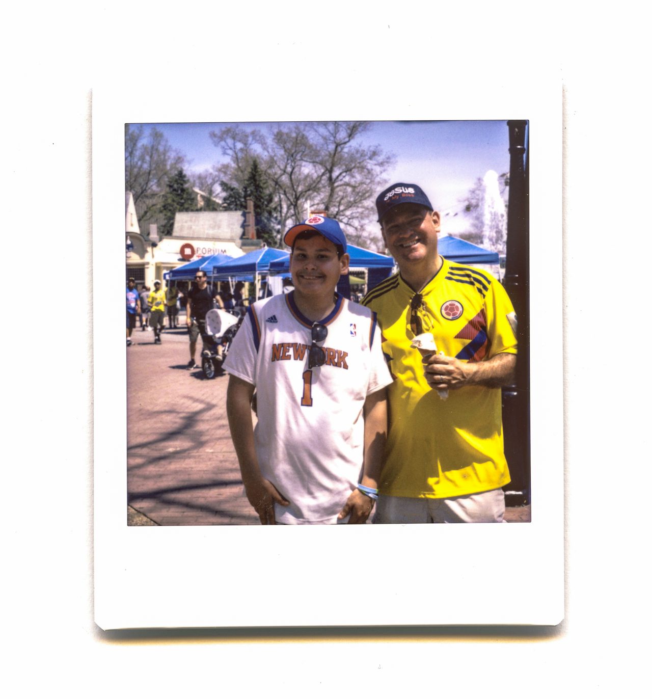 An adult and a young man smile together near the Main Street Fountain of the park.