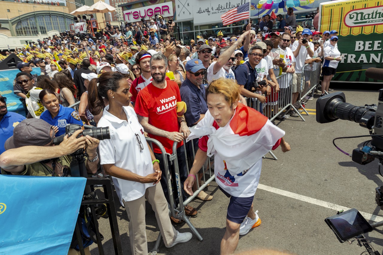 Max Suzuki bounds up to the stage, wrapped in a Japanese flag.
