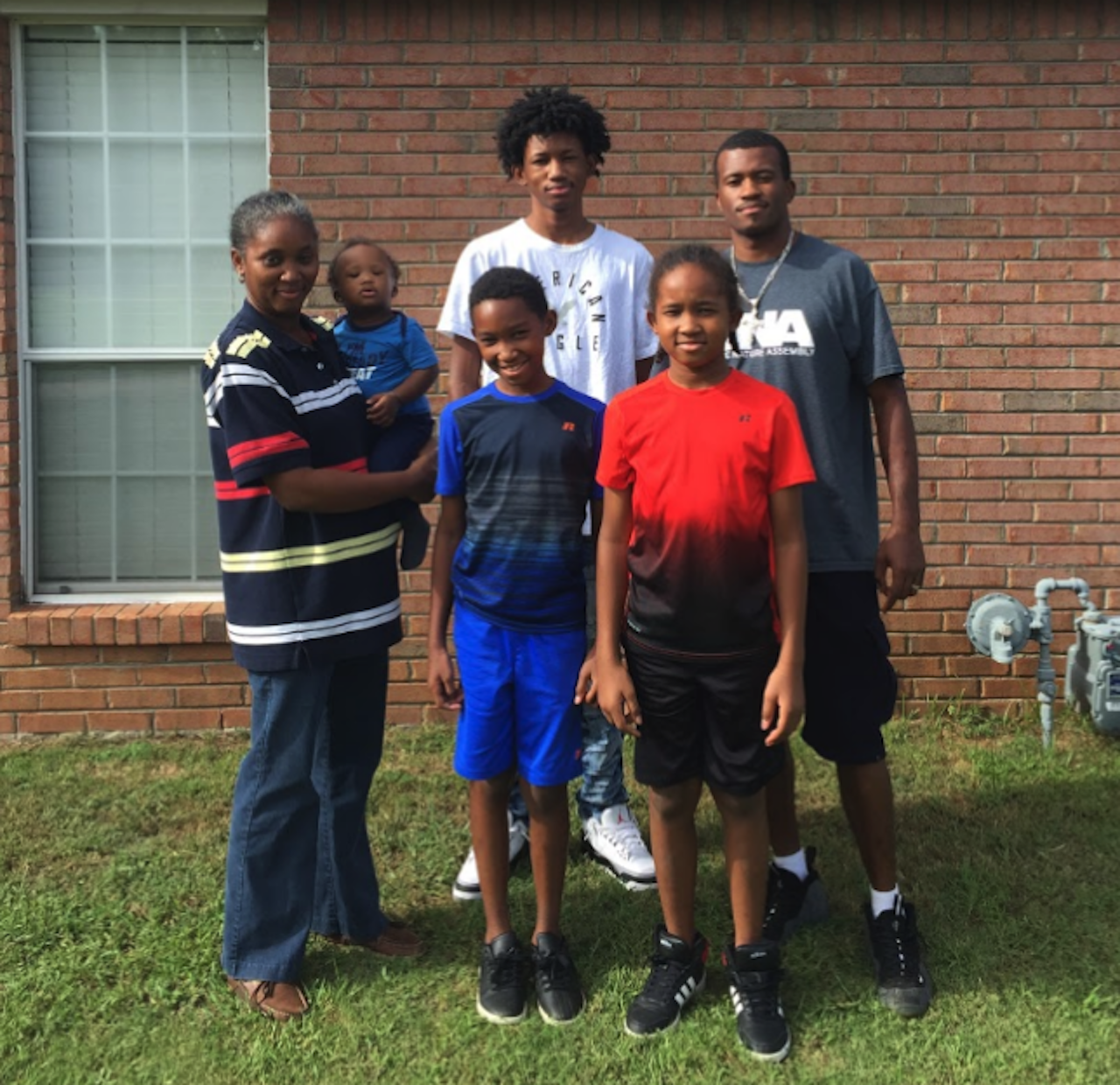 The Smith family in front of their home in Montgomery, Alabama. [Below] The family’s two quilters stand together. Julian holds up two small patches he’s been working on lately; DeShuan’s work is all down at the Collective where it’s listed for sale.
