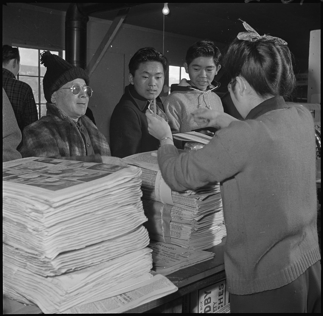 Japanese Americans purchasing camp newspaper.