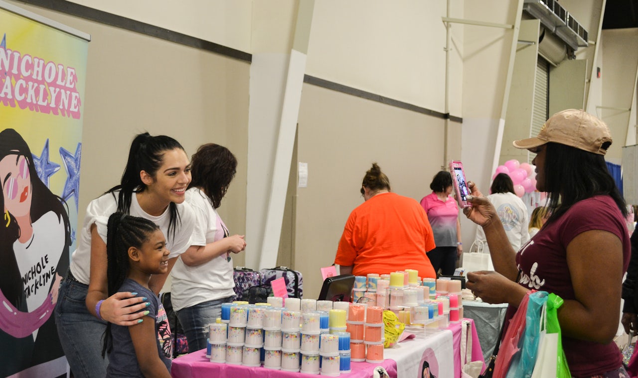 Nichole Jacklyne takes photo with a fan at her booth.